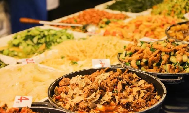 摆放着自助餐形式的大锅菜与各种蔬菜的自助取餐食堂
